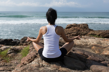 Fototapeta na wymiar Yoga woman meditation at the seaside rock cliff edge