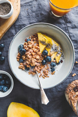 Top view of breakfast table for one, crunchy granola with fresh berries and cream or milk. Flat lay, healthy eating