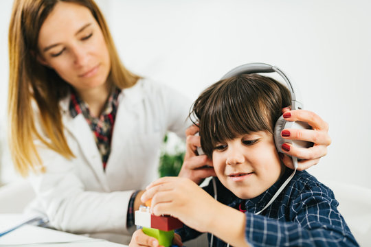 Pediatric Audiologist Testing Hearing With A Little Boy