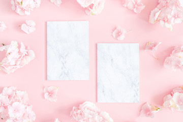 Flowers composition. Hydrangea flowers,paper blank on pastel pink background. Flat lay, top view, copy space