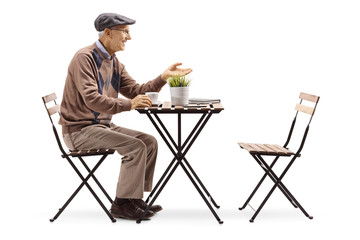 Senior man sitting at a table drinking coffee and gesturing a conversation - Powered by Adobe