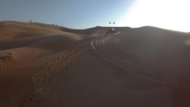 Aerial drone slow motion tracking shot of a dune buggy going up the sand dunes