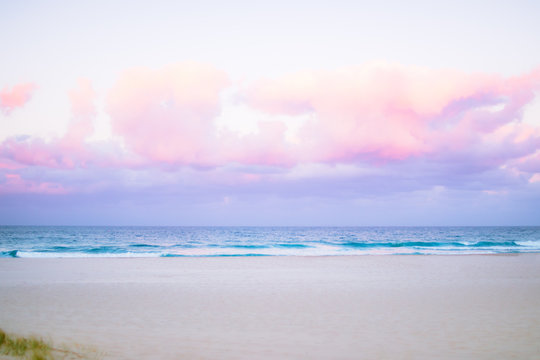 pretty pastel colour sky pink purple blue with fluffy cloud on beach 