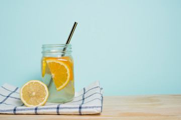 Summer soft drink. Lemon and orange homemade lemonade on a checkered towel, on a wooden table and a blue background. Empty space for text