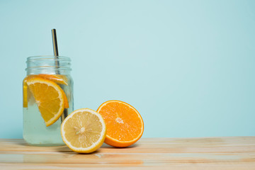 Summer soft drink. Homemade lemon and orange lemonade on a wooden table and a blue background. Empty space for text