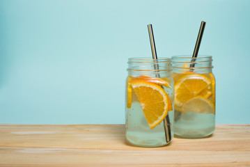 Summer soft drink. Homemade lemon and orange lemonade on a wooden table and a blue background. Empty space for text