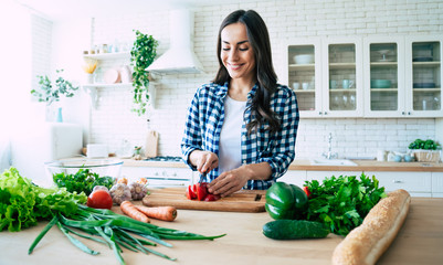 Beautiful young woman is preparing vegetable salad in the kitchen. Healthy Food. Vegan Salad. Diet....