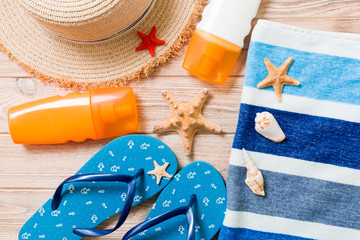 flip flops, straw hat, starfish, sunscreen bottle, body lotion spray on wooden background top view...