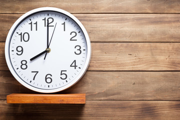 wall clock at shelf on wooden background