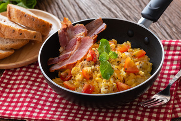 Scrambled egg with tomato sliced, bacon grill on pan and breads, Homemade Breakfast.