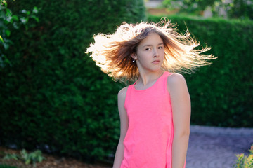 Backlight portrait of preteen girl with flying blowing hair shining in sun. Backlit. Summer energy...