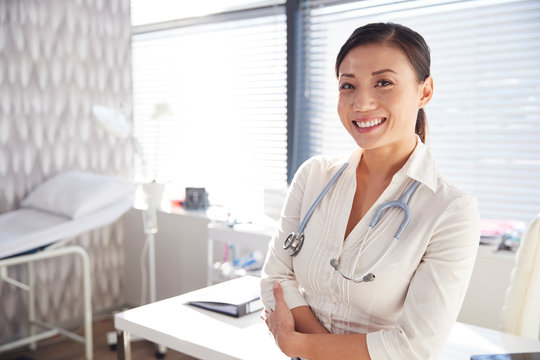 Portrait Of Smiling Female Doctor With Stethoscope Standing By Desk In Office