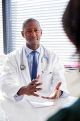 Female Patient In Consultation With Doctor Sitting At Desk In Office