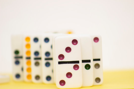 Domino game pieces standing in a row on yellow background