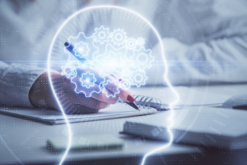 Double exposure of woman's writing hand on background with brain hologram. Concept of brainstorming.