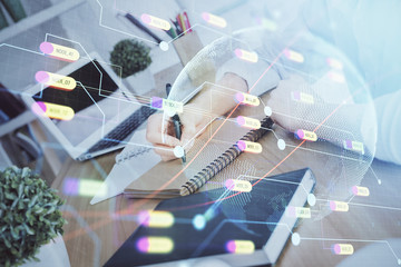 Double exposure of hands making notes with world map hologram and data theme icons. Concept of...
