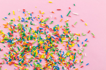 Fototapeta premium Sprinkles on pink background - Many multi-colored sprinkles on pink - top view