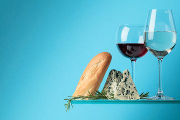 Blue cheese with baguette, wine and rosemary on a blue background.