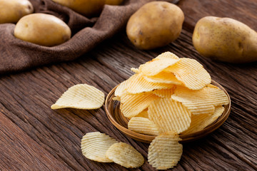 Appetizer and Snack food. Crispy potato chips on plate with fresh potatoes.