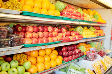 Various colorful ripe fresh fruits on shelves in grocery store