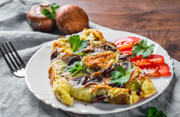 omelette with mushrooms in white plate on wooden table background