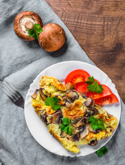 omelette with mushrooms in white plate on wooden table background
