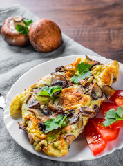 omelette with mushrooms in white plate on wooden table background