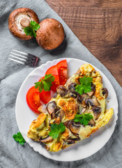 omelette with mushrooms in white plate on wooden table background