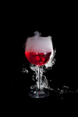 A cup of red cold cocktail with dry ice smoke
