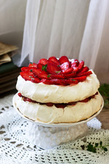 Pavlova meringue homemade cake with strawberries and cream on the background of an old photo album. Rustic style.