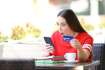 Shocked student paying online with credit card in a bar