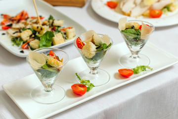 Salad in cups, with tomatoes, sauce and greens.