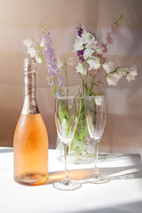 a bottle of cold pink champagne with glasses