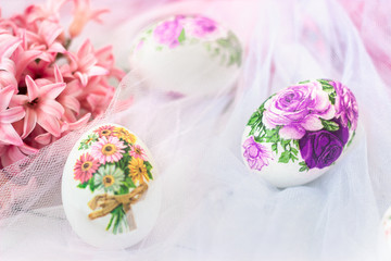 Beautiful Easter eggs decorated with paper napkins and flowers on white tulle background; decoupage technique