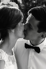 stylish gorgeous happy bride and groom kissing at wedding reception, emotional cheerful moment