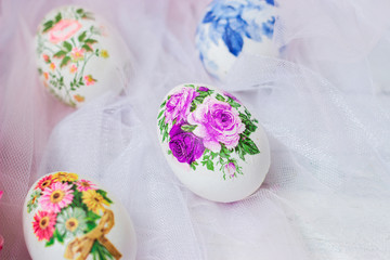 Decorated Easter eggs and flowers on white tulle background; decoupage technique