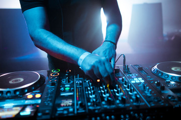 Fototapeta na wymiar DJ mixing tracks on a mixer in a nightclub
