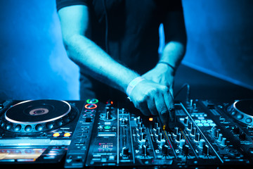 DJ mixing tracks on a mixer in a nightclub