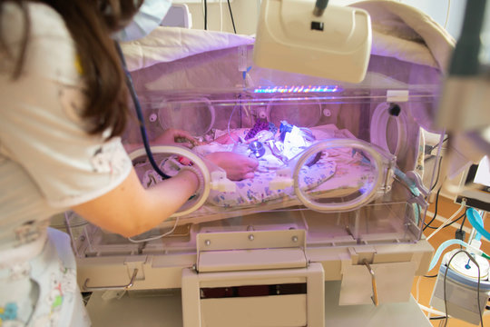 Female Doctor Examining Newborn Baby In Incubator. Close Up Female Hands With A Stethoscope