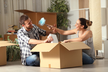 Fototapeta na wymiar Happy couple joking unboxing belongings moving home