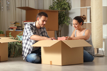 Serious couple boxing belongings on the floor moving house