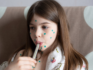 a girl with chickenpox measures her temperature