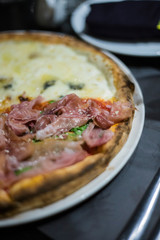 Pizza in a restaurant with meat and cheese