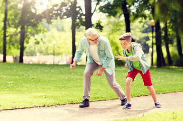 Obraz premium family, generation and people concept - happy grandfather and grandson racing at summer park