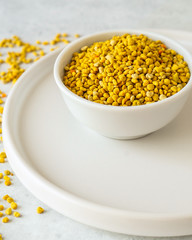 Bee pollen in a bowl on white stone background