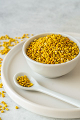Bee pollen in a bowl on white stone background