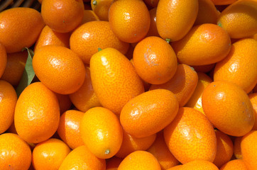 Fresh juicy kumquats in a basket in the market. Orange background of fresh oranges. Closeup