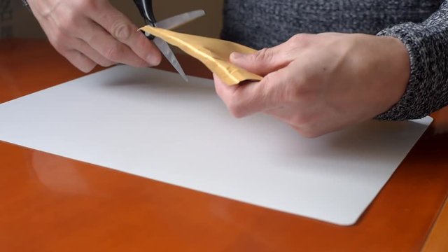 Closeup of man unpacking envelope with parcel at home