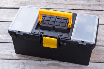 Black and yellow tool box. Tool case on wooden background. Repair concept.