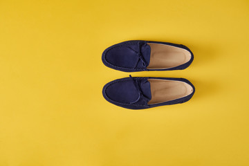 Dark blue suede man's moccasins shoes over yellow background,